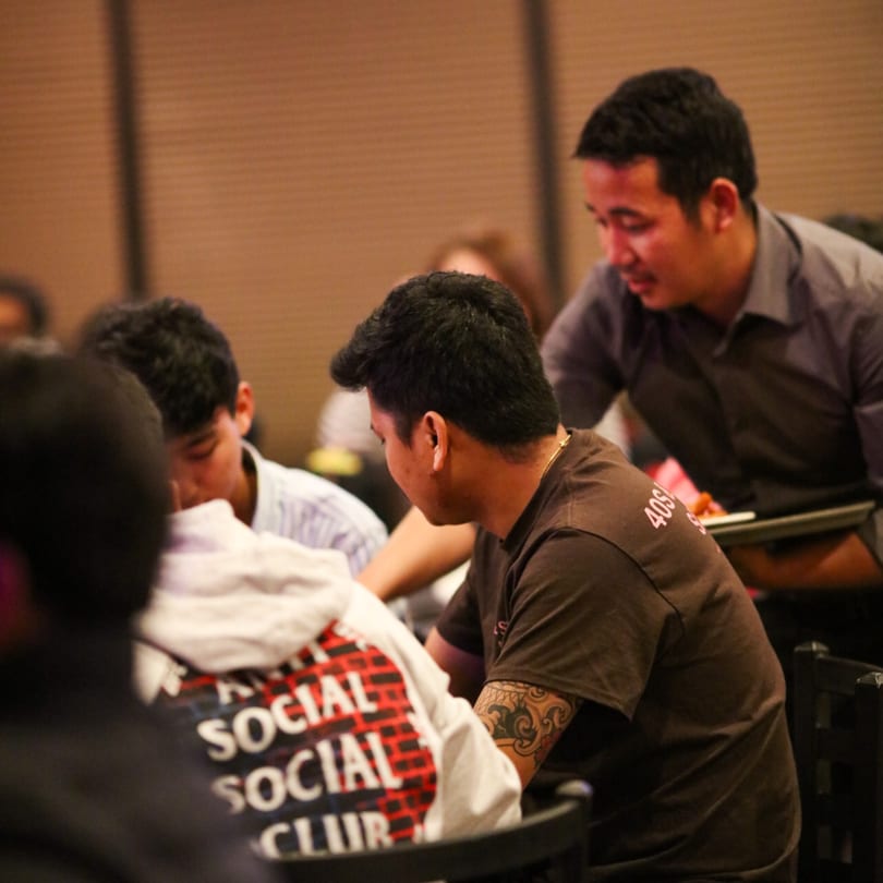 A waiter at Durbar Nepalese And Indian Bistro serves customers seated at a table.