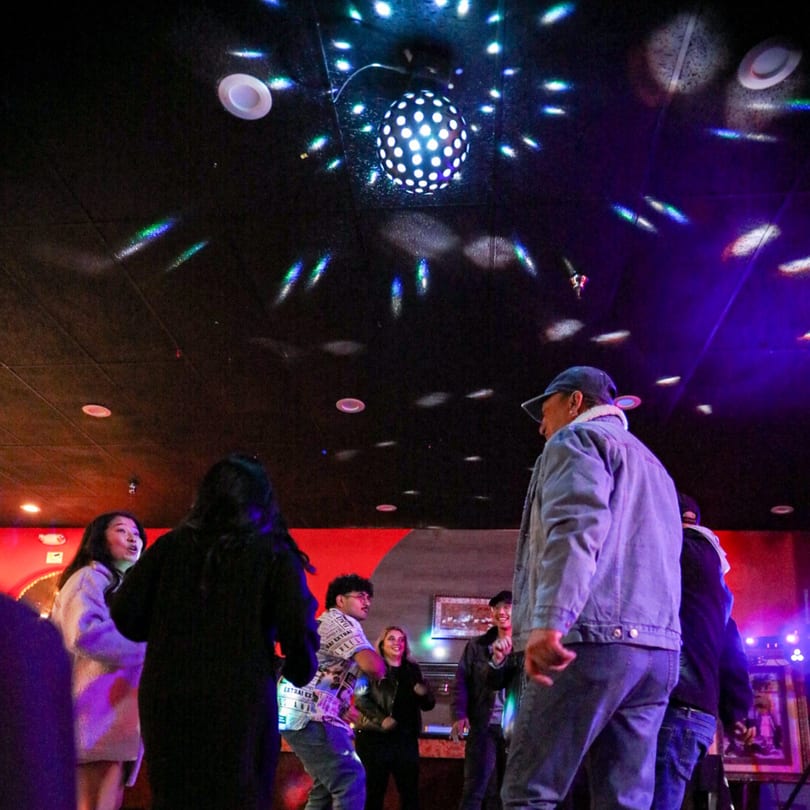 People dancing under a disco ball and colorful lights at Durbar Nepalese And Indian Bistro.