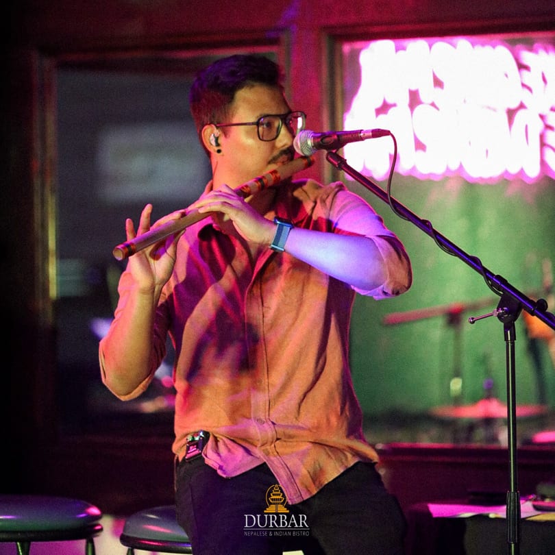 A musician playing a flute on stage at Durbar Nepalese and Indian Bistro.